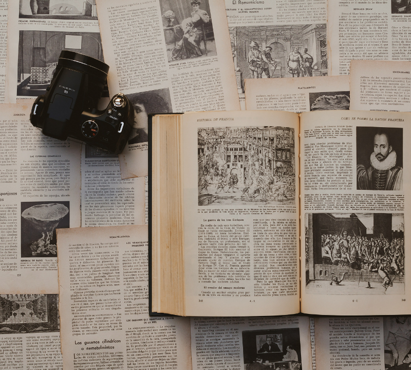 Investigadora de Ascendere Genealogías analizando documentos históricos con una lupa sobre un escritorio de madera.